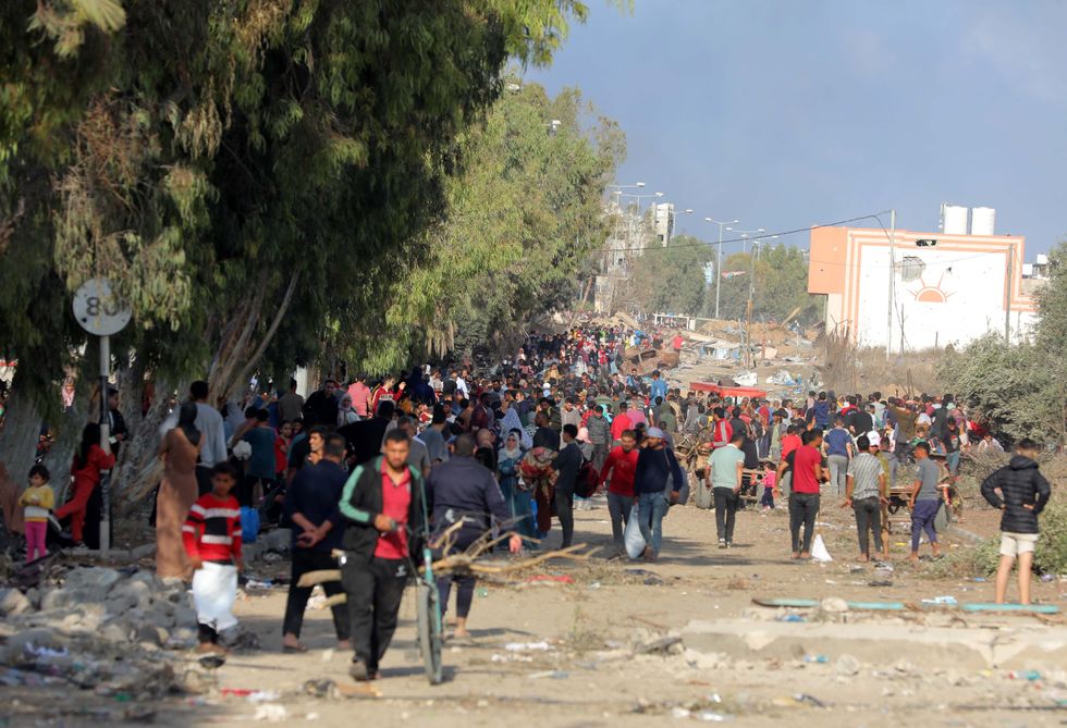 A crowd of people on the Gaza strip gathered and walking down the road fleeing the city