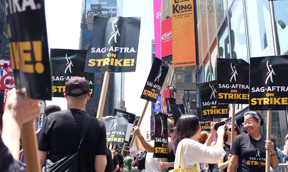 A crowd of SAG-AFTRA union protestors hold up signs in front of the Rockefeller Center in New York.