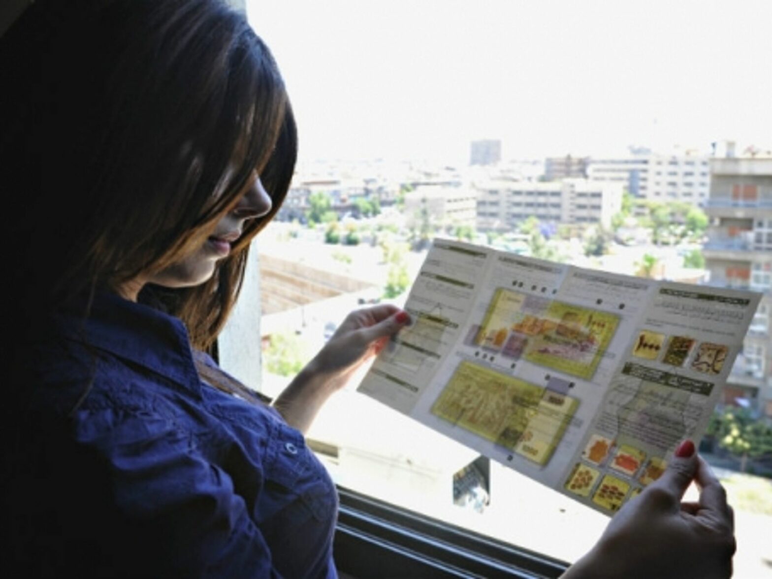 A Damascus woman reads a brochure about the new 1,000 Syrian Pounds bill issued last June.
