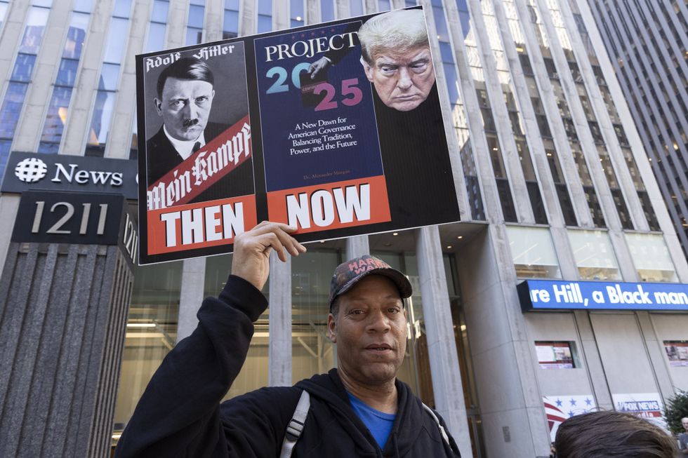 A demonstrator holds a sign that reads 'Mein kampf Project 2025 Then Now' at a protest organized by the activist group Rise & Resist demonstrate outside of Fox News in New York.