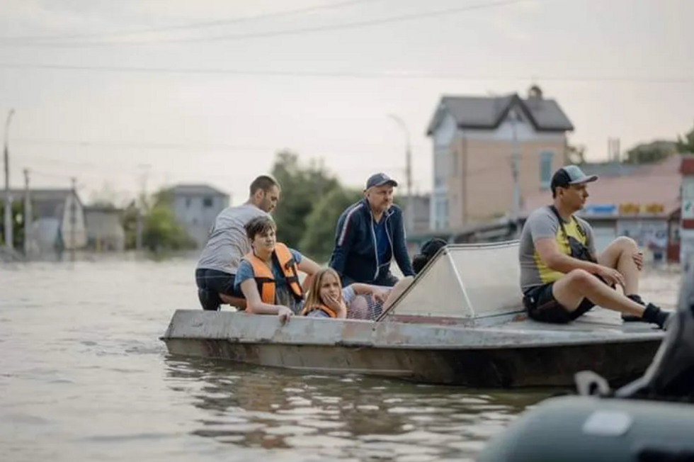A family rescued by boat from the floods following the explosion of a dam in Ukraine.