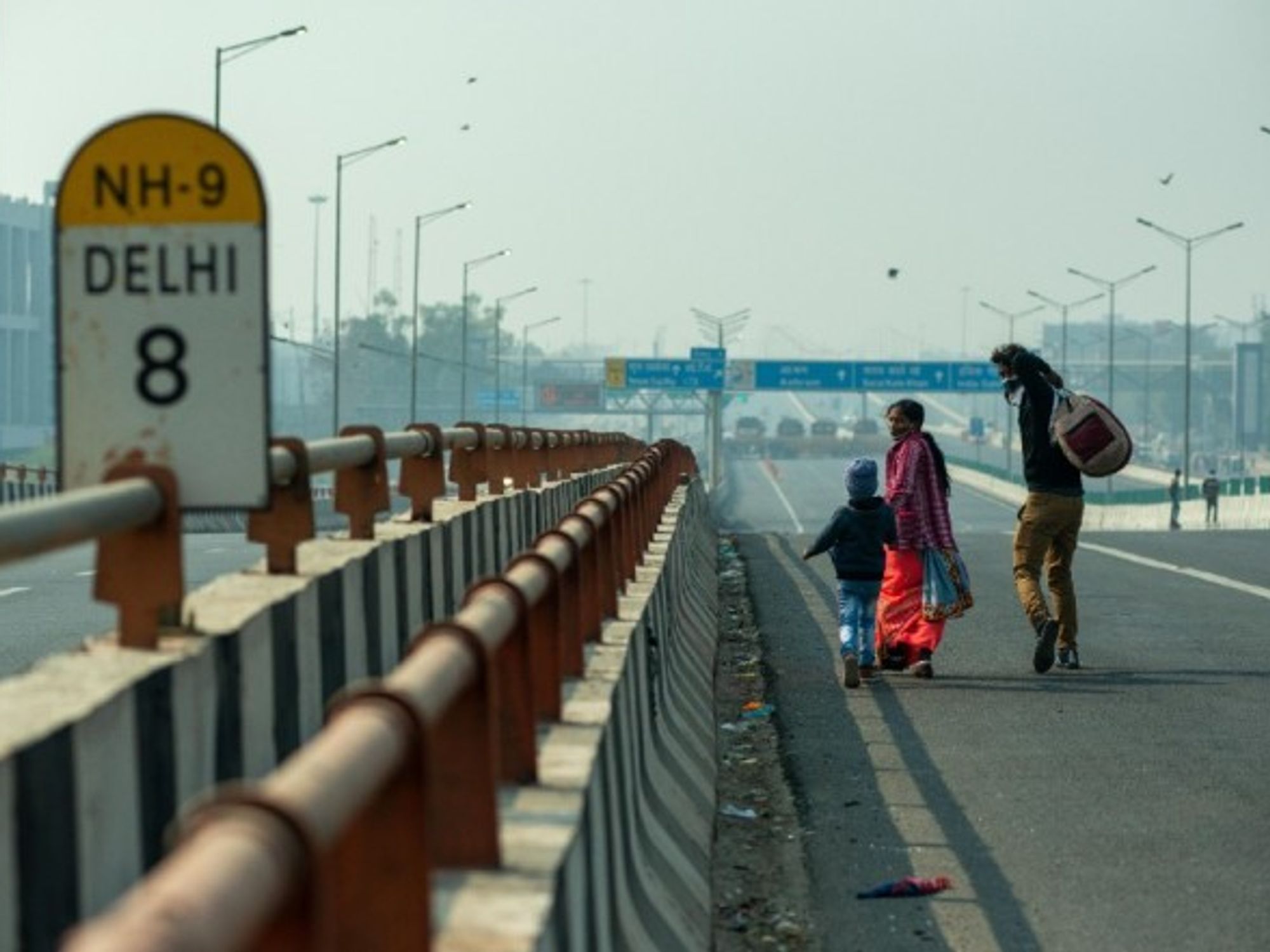 A family walking on an empty road towards Delhi in December 2020, amid farmers' protests against the government's new agricultural reforms.
