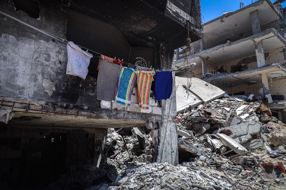 A family who chose to stay in their house, destroyed by Israeli attacks, hang clothes to dry in the middle of the rubble.