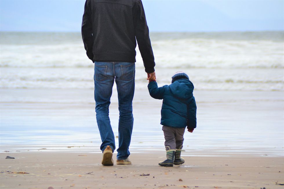 A father and his son walking on a beach in Ireland.