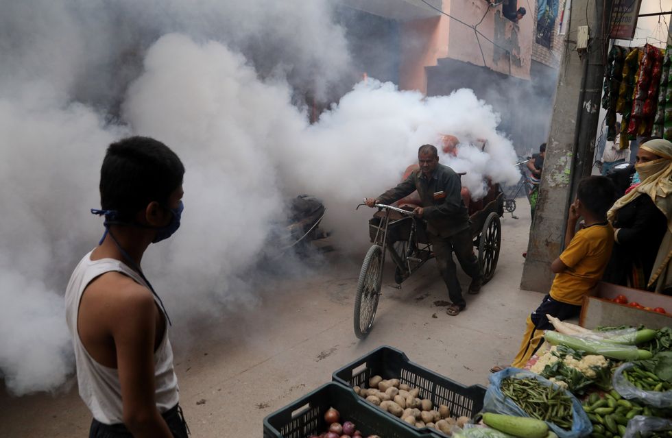 A fumigation worker fumigates inside a residential area as a precautionary measure against the spread of dengue disease as part of the fogging campaign in Shalimar Bagh.