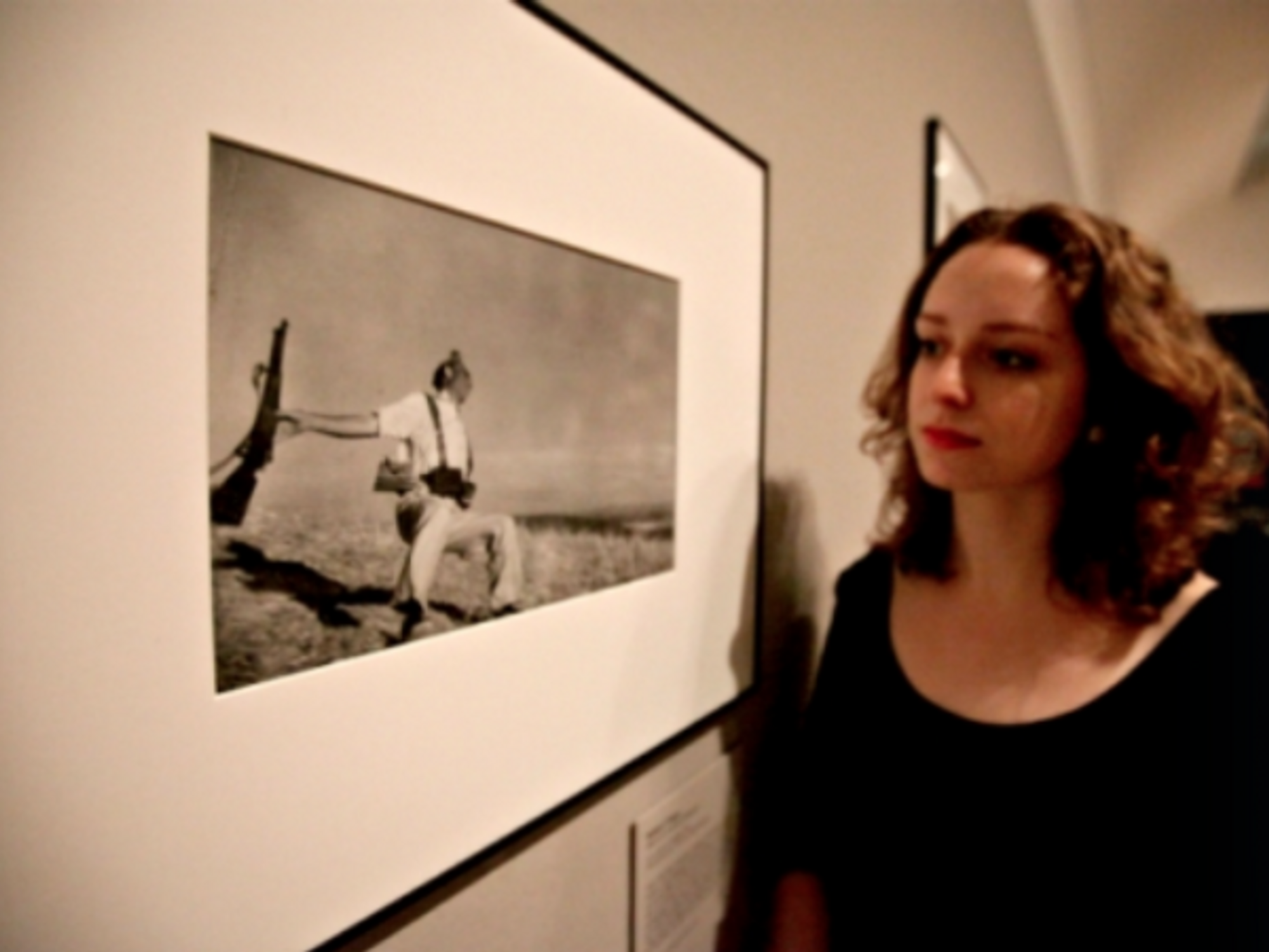 A gallery assistant looks at Robert Capa's
