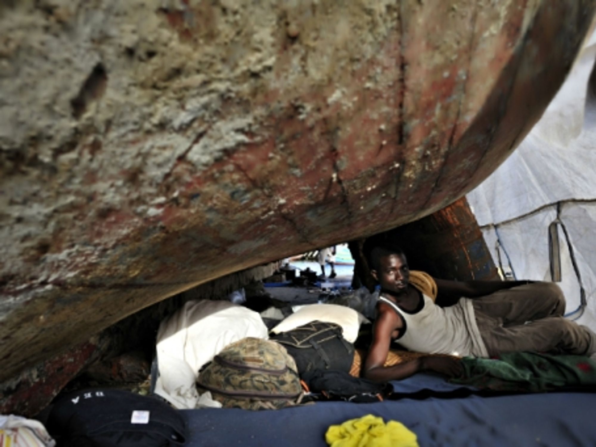 A Gambian migrant living under an boat outside Tripoli, Libya