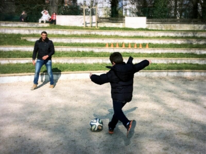 A Garrigan boy playing soccer with a Syrian refugee in Paris' Parc Sainte-Perrine
