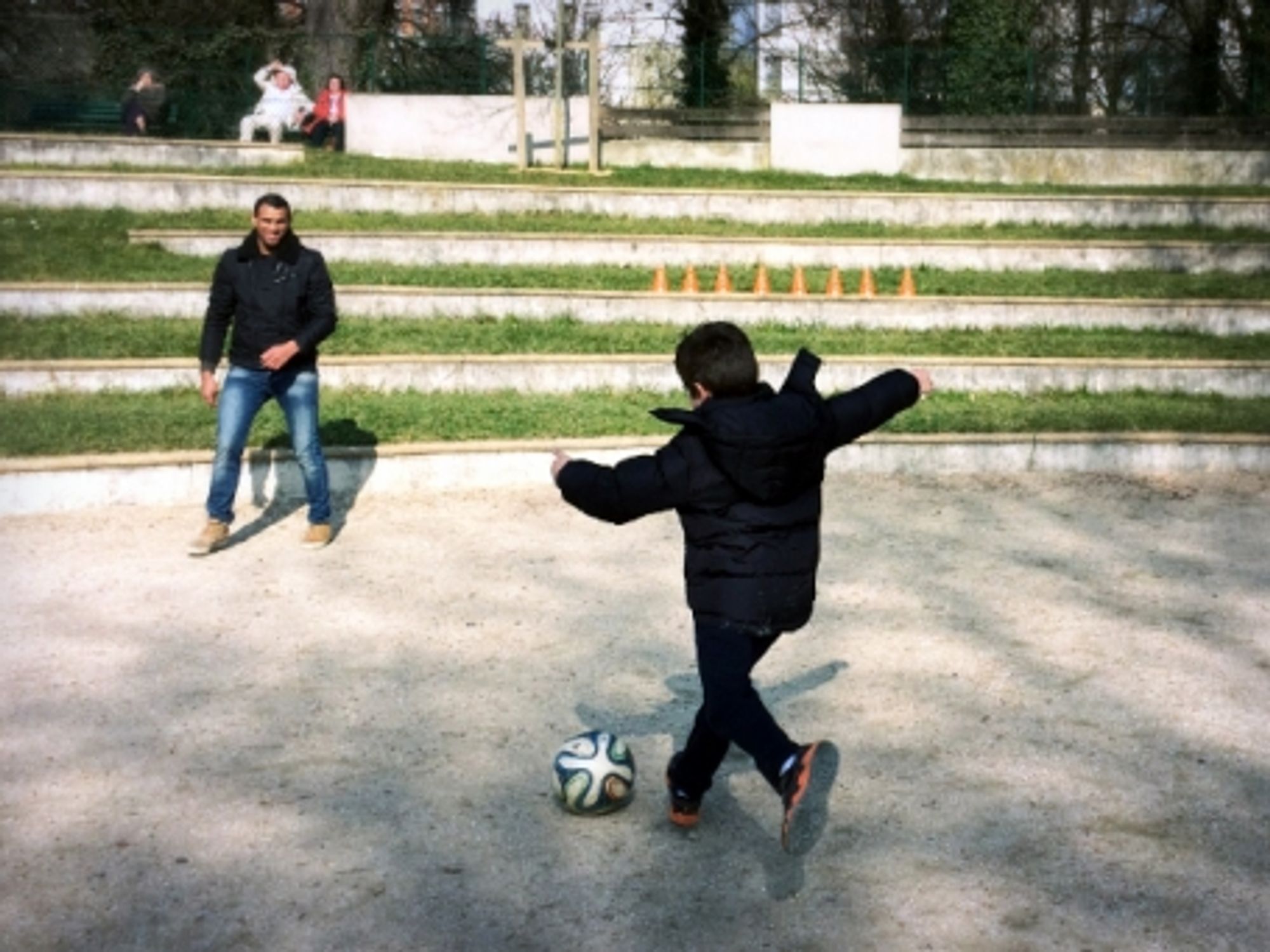 A Garrigan boy playing soccer with a Syrian refugee in Paris' Parc Sainte-Perrine