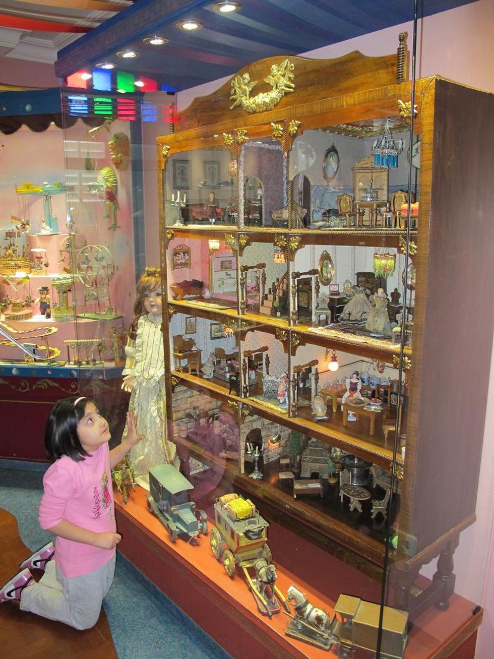 A girl admires a large doll house.​