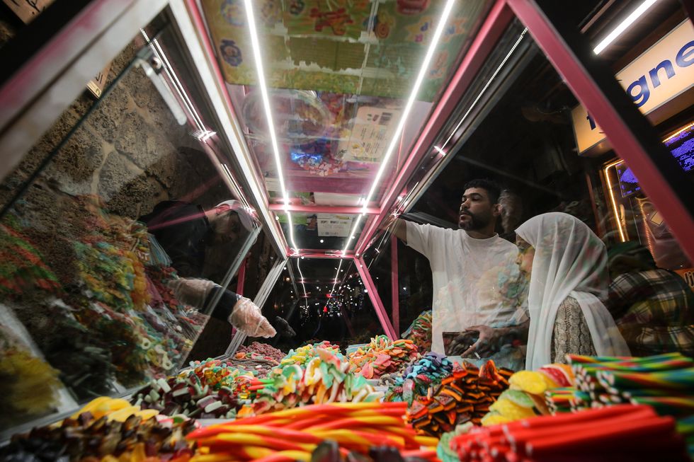 A girl buys gummies from a street vendor in the southern Lebanese city of Sidon during a night out following Iftar.