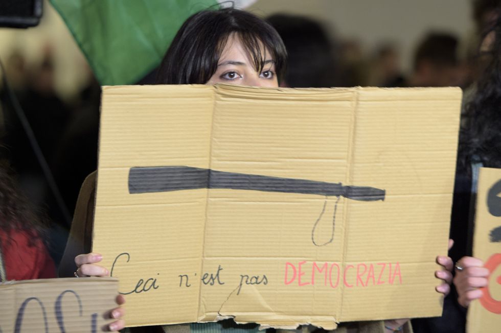 A girl shows a sign with a drawing of a truncheon and the words 'this is not democracy' during the protest against police charges at the pro-Palestine demonstrations in Pisa, Florence and Catania.