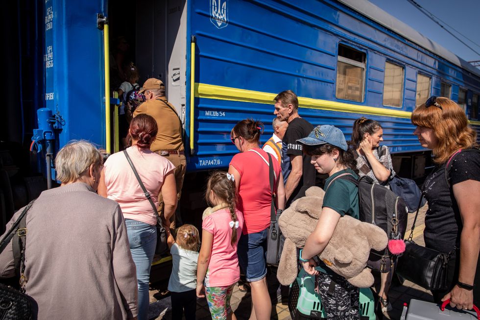 A girl with a doll is amongst families boarding the evacuation train in Pokorvsk.