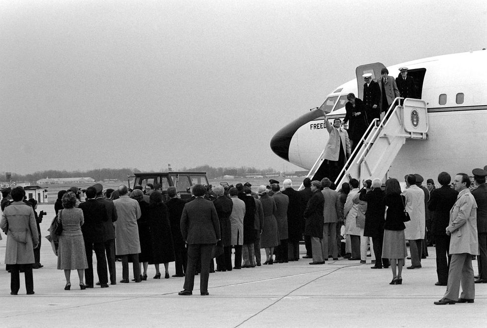 A group of American hostages smiles as they are greeted by family and officials upon their return from Iran.