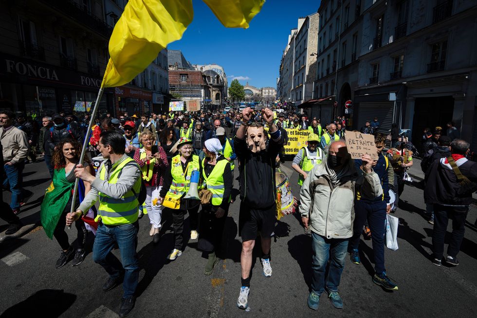 A group of protesters wearing yellow vests and holding banners.