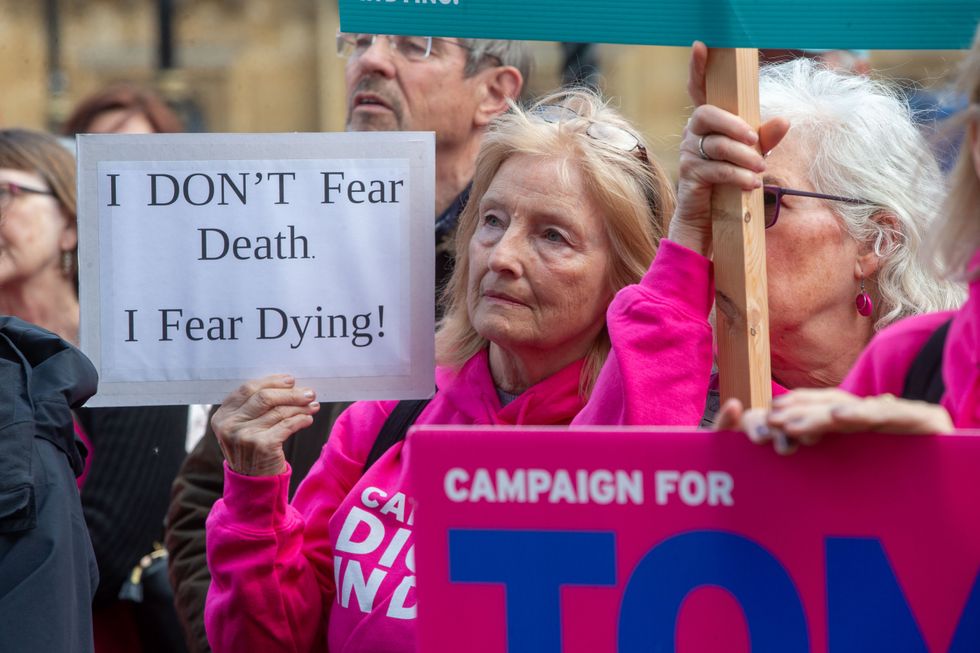 A group of women holding signs at a protest in support of assisted suicide.