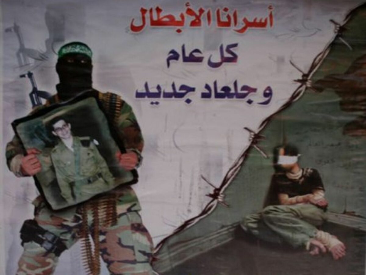 A Hamas soldier holds a picture of Gilad Shalit on a Hamas poster.