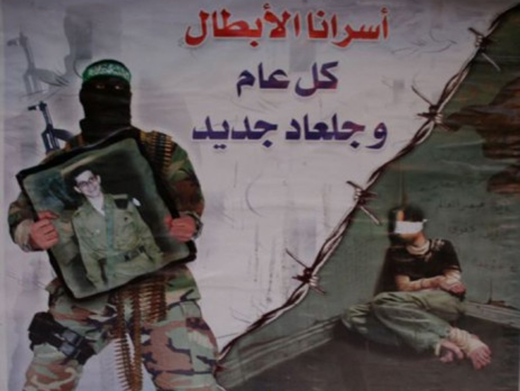 A Hamas soldier holds a picture of Gilad Shalit on a Hamas poster.
