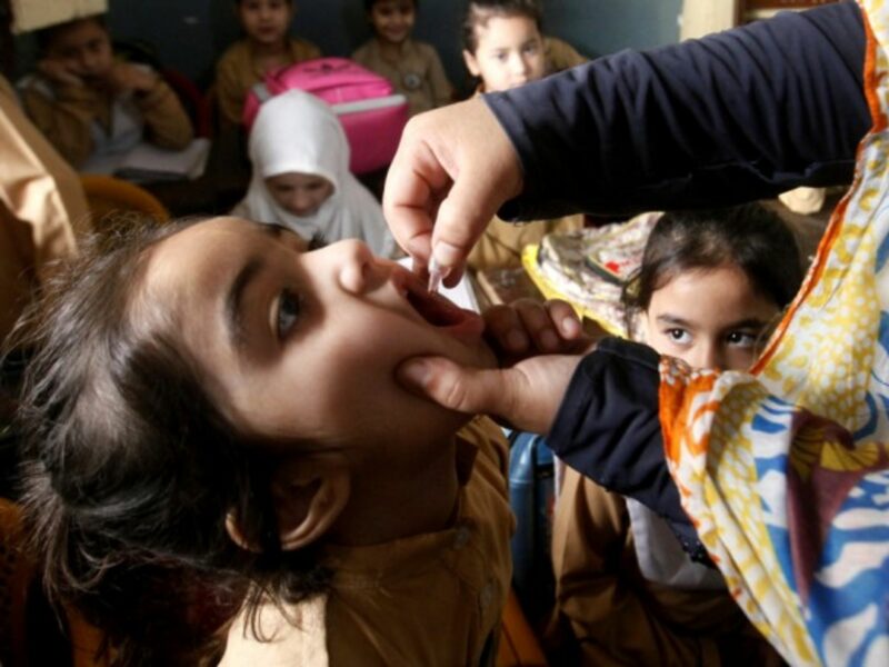 A health worker gives a polio vaccine to a child in Pakistan.