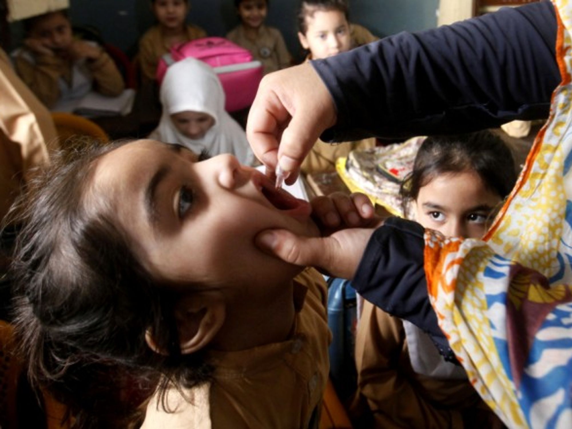 A health worker gives a polio vaccine to a child in Pakistan.
