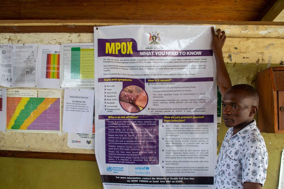 A health worker hands a sign with information about how to ward off mpox. The area around the Mpondwe border that divides Uganda and DRC is a major entry point for people suspected of having mpox.