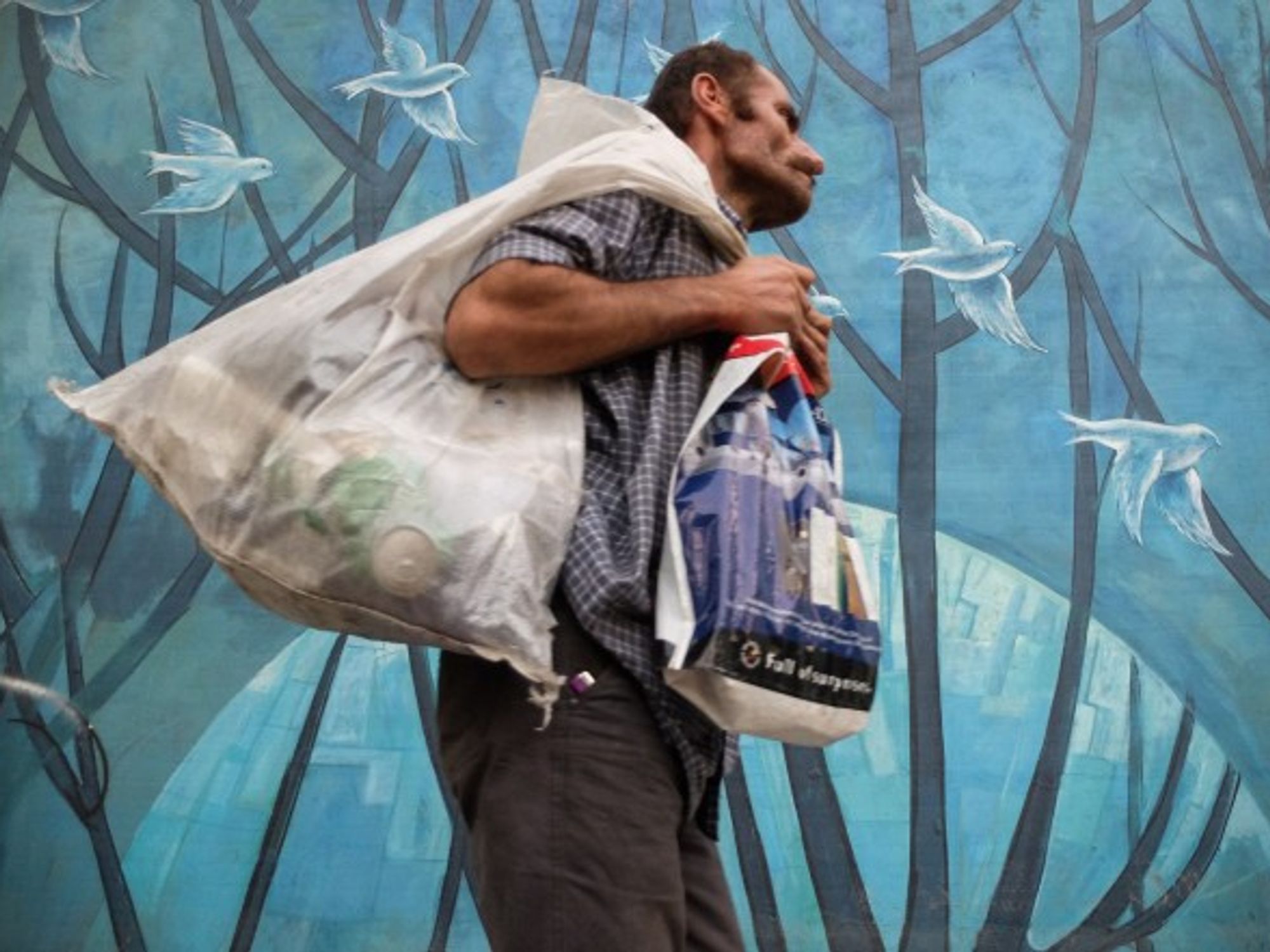 A homeless man walks past a mural in Tehran, Iran.