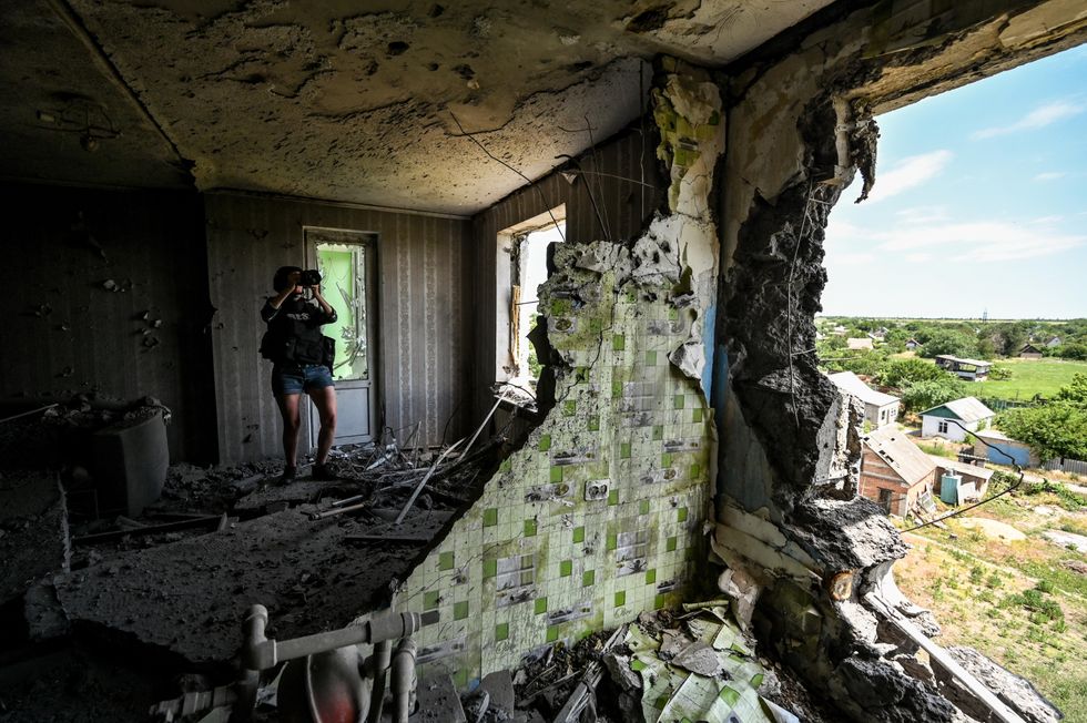 A journalist taking pictures in the village of Komyshuvakha, southern Ukraine, after it was bombarded by Russian forces