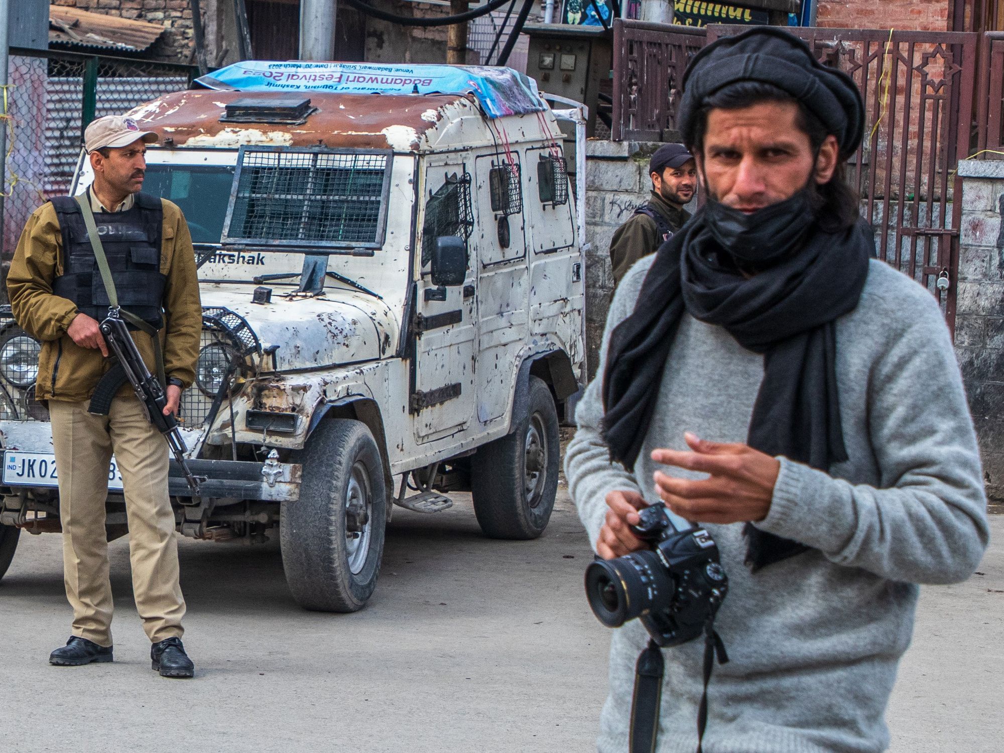 A Kashmiri photojournalist walks past Indian policemen standing on guard outside the closed Kashmir's Grand Mosque or Jamia Masjid.