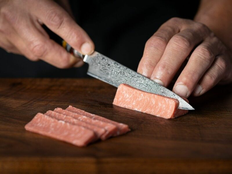 A knife cuts through cell-culture-grown seafood meat.