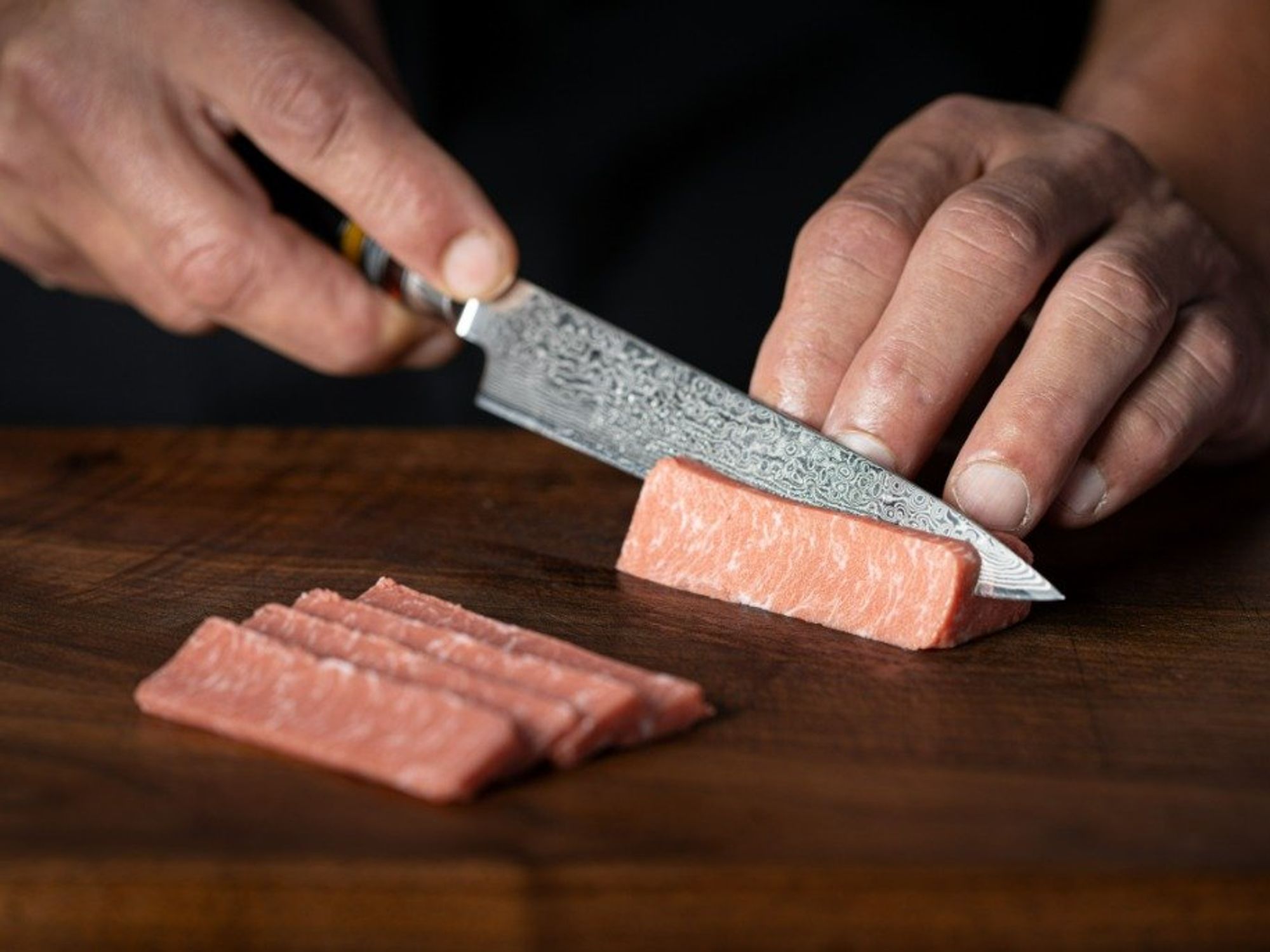 A knife cuts through cell-culture-grown seafood meat.