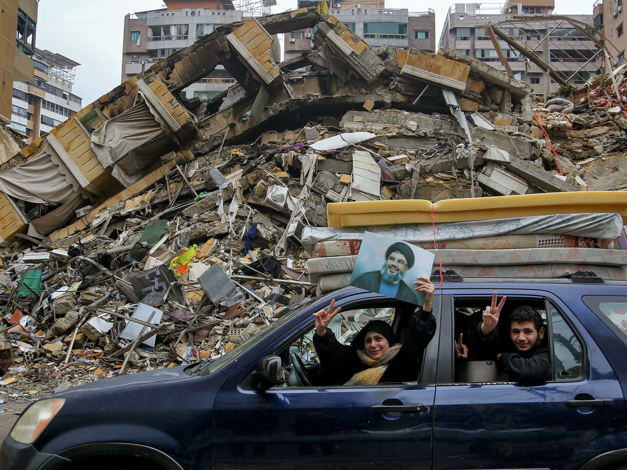 A Lebanese family holds a photo of assassinated pro-Iranian Hezbollah leader Hassan Nasrallah as they pass in front of a destroyed building following a ceasefire between Israel and the Lebanese Hezbollah militia, Lebanon, Beirut, Nov. 27, 2024. ​