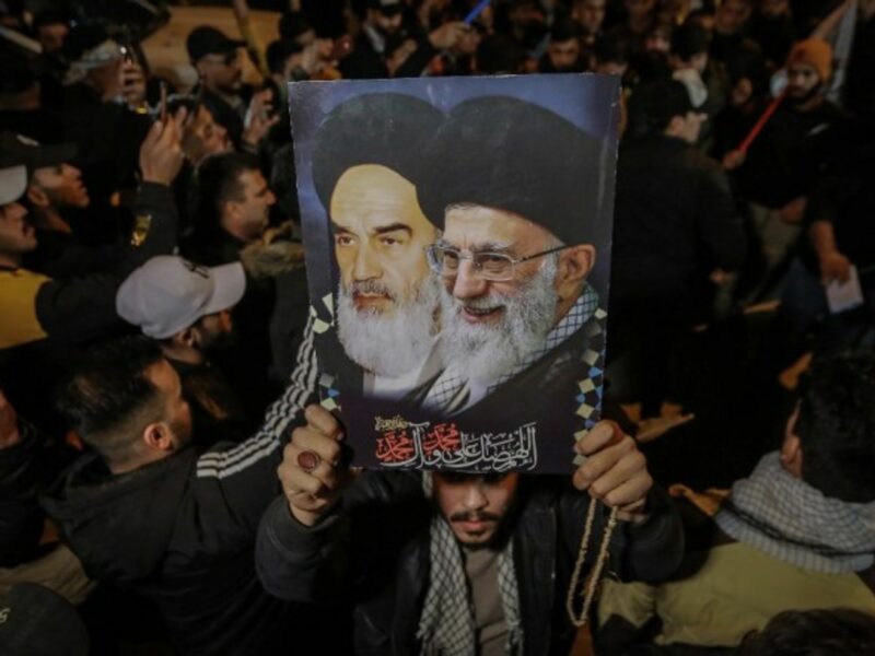 A man carries a poster of the Ayatollahs Khamenei and Khomeini.
