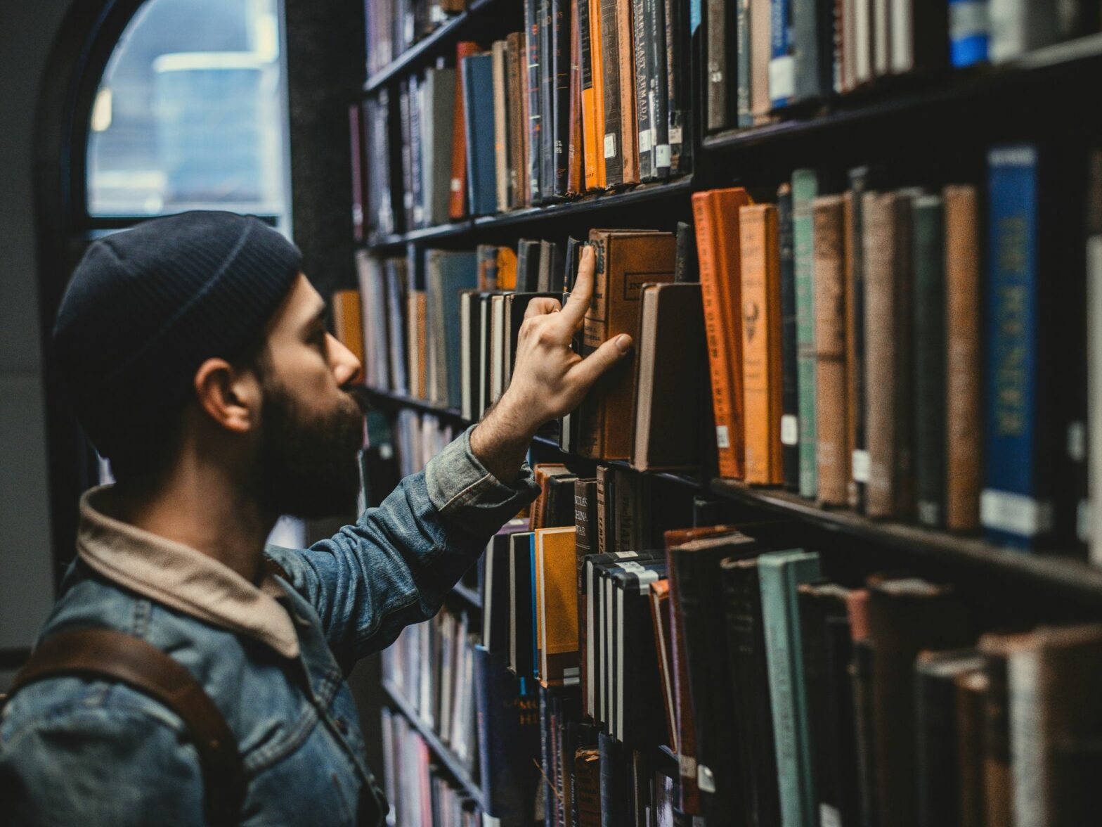 A man choosing a book in a library.