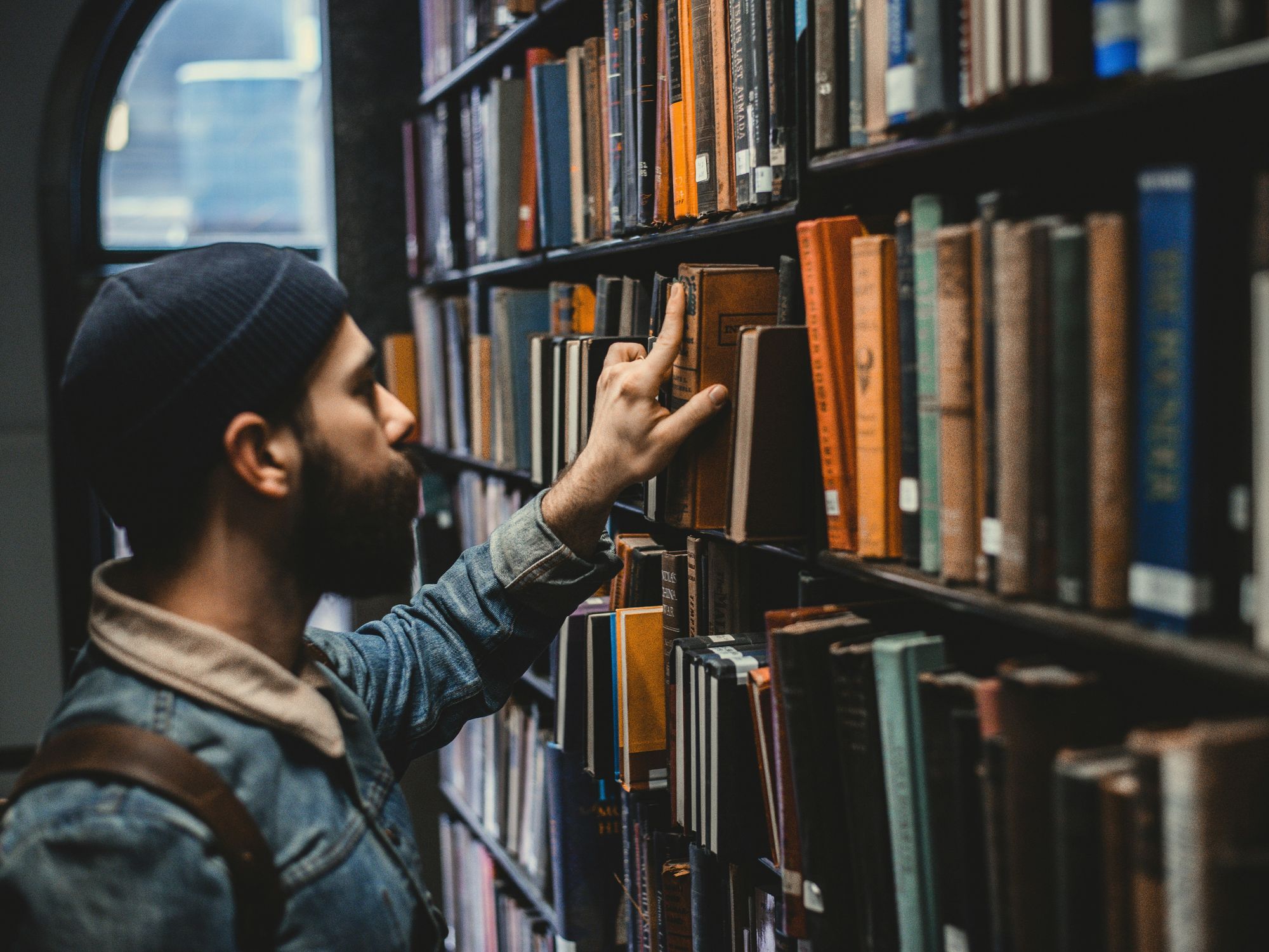 A man choosing a book in a library.