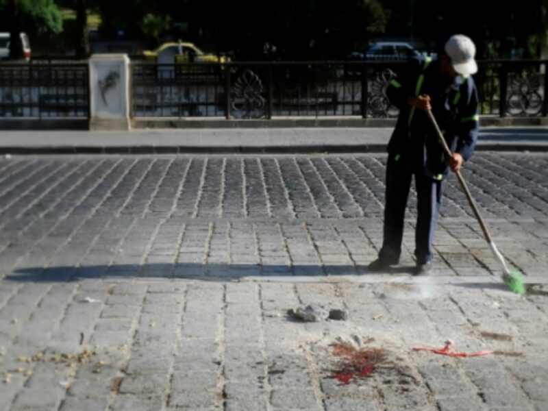 A man cleans blood from the site of an explosion in Damascus on Aug. 12