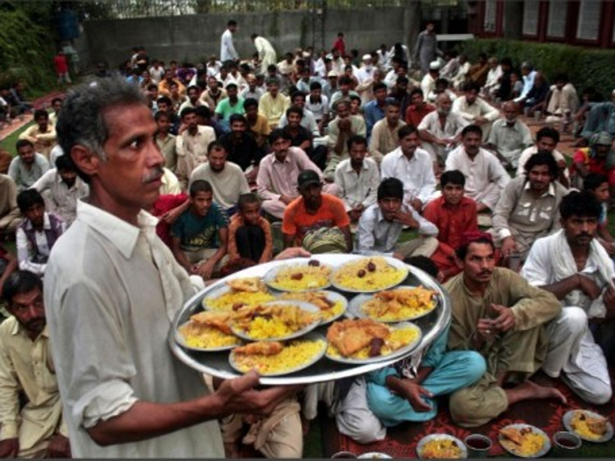 A man distributes Iftar food to Muslim devotees waiting to break their fast during the sacred fasting month of Ramadan.