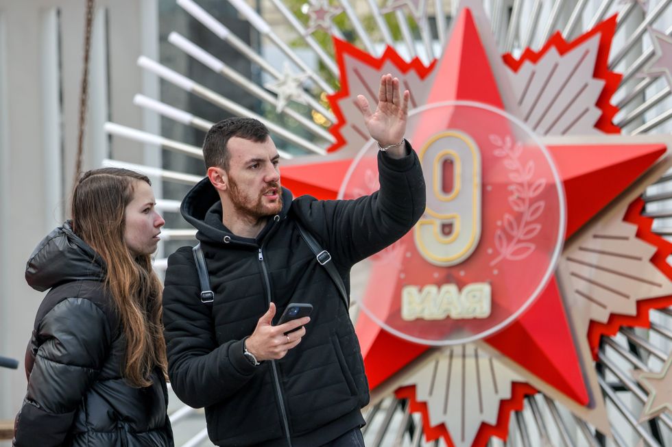 A man gives directions to a woman infront of a red star installation
