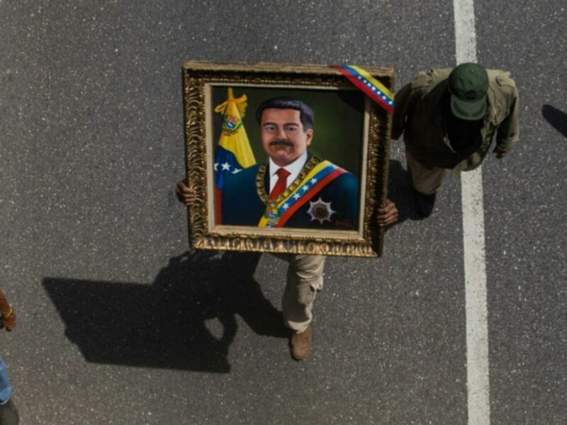 A man holding a portrait of Maduro during a rally on May 1