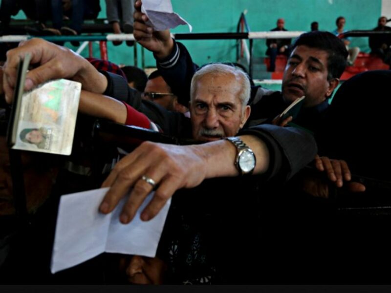 A man holds out his passport while trying to get through the border crossing in Rafah