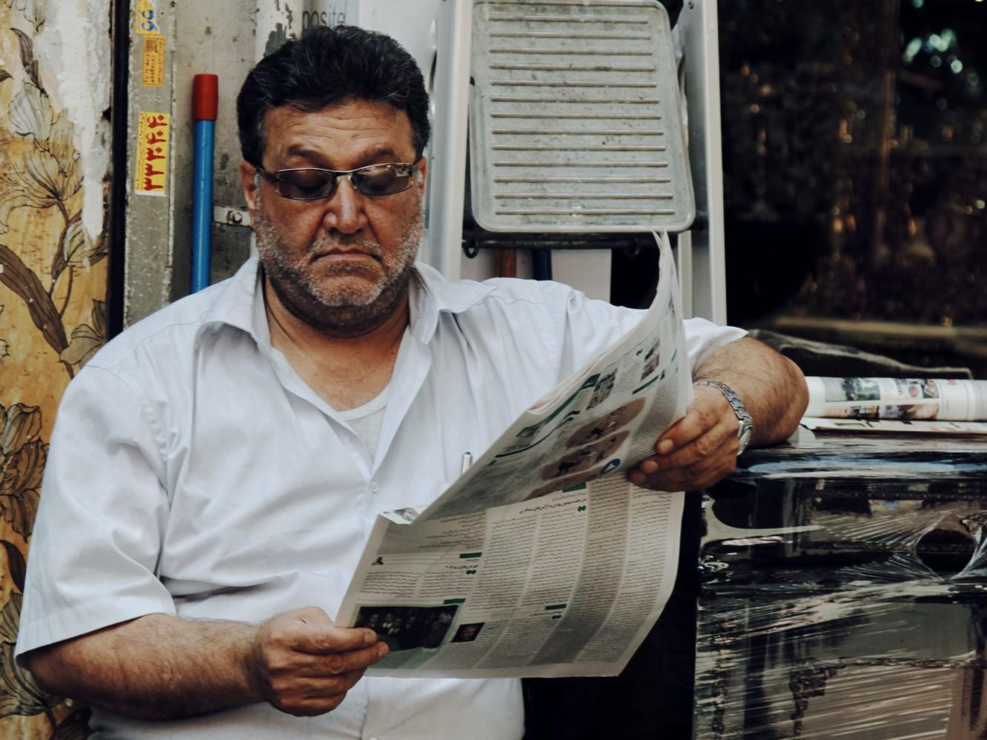 A man in a white polo shirt reading the news