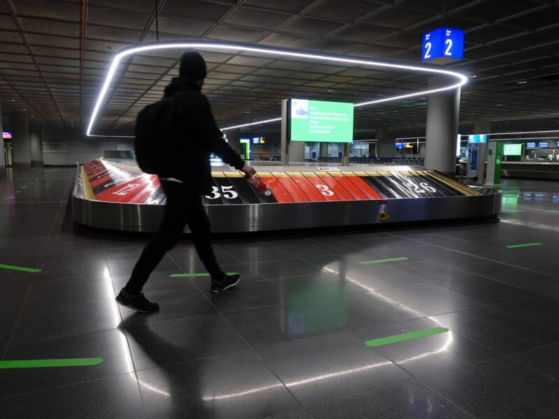 A man in black walks through baggage claim