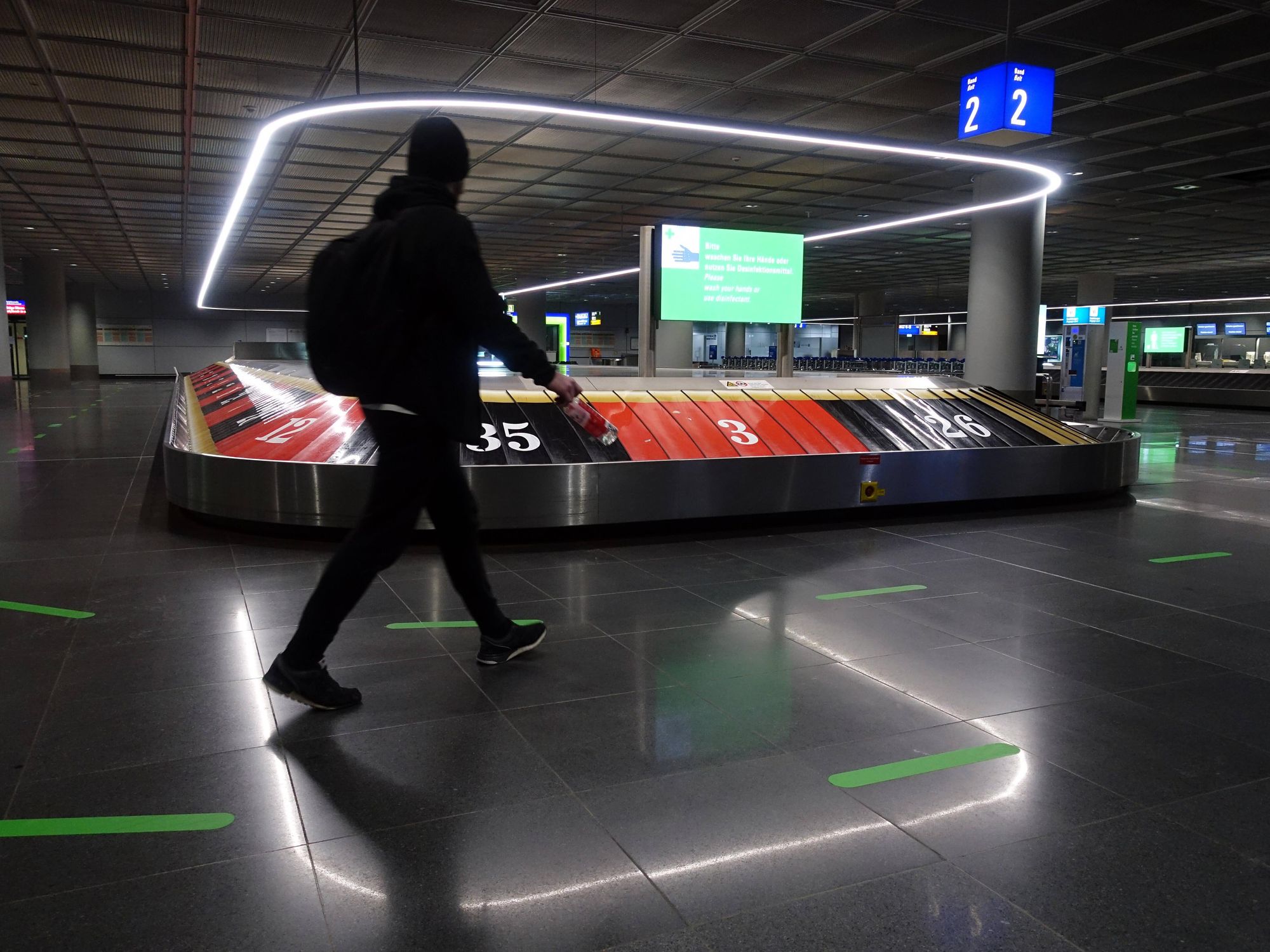 A man in black walks through baggage claim