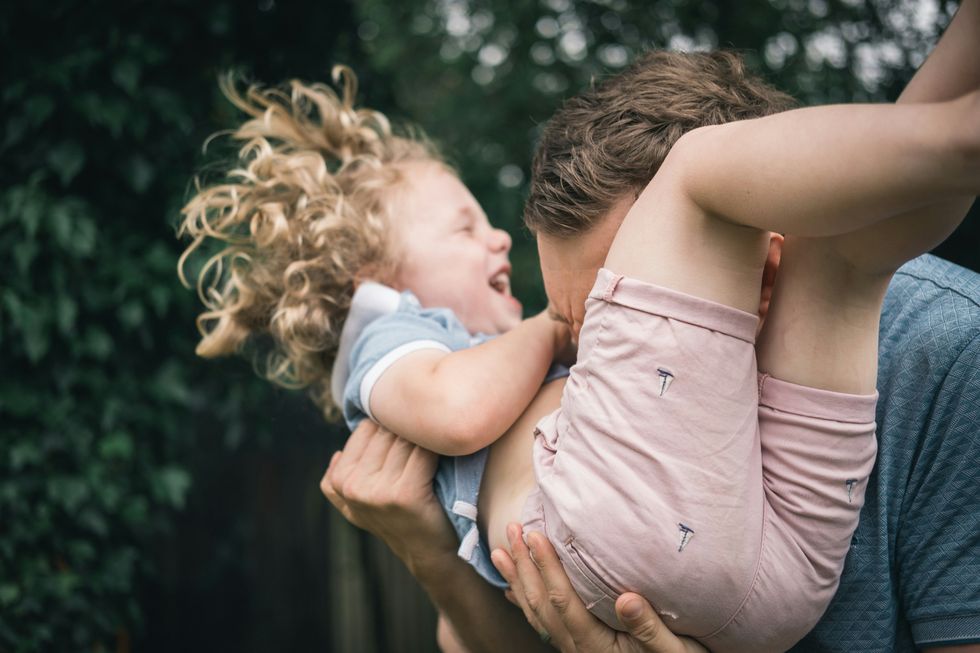 A man playing with his daughter outside