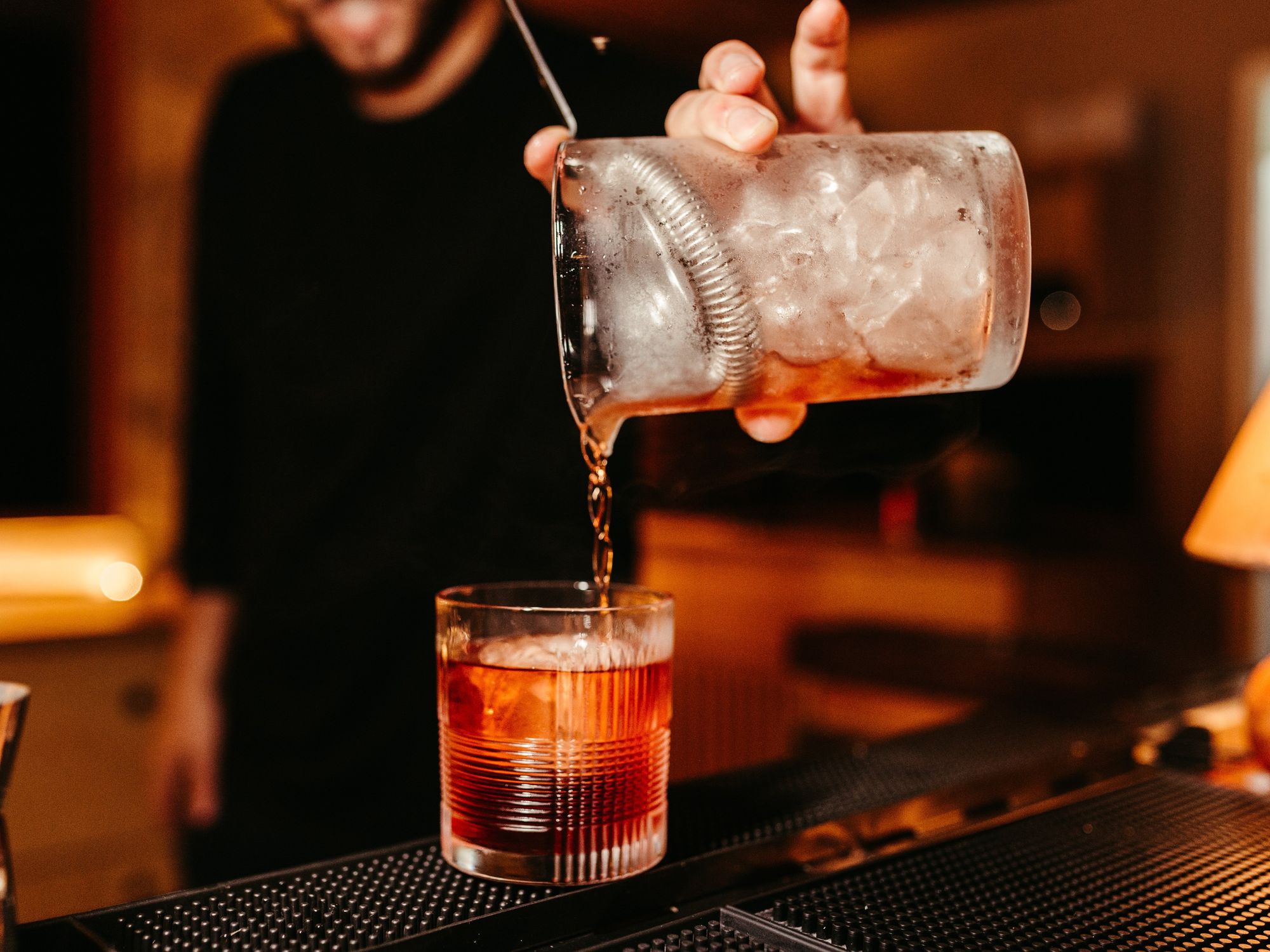 A man pours Negroni into a glass