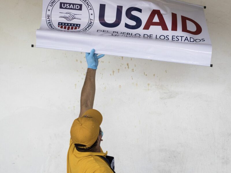 A man reaches up to take down a USAID sign