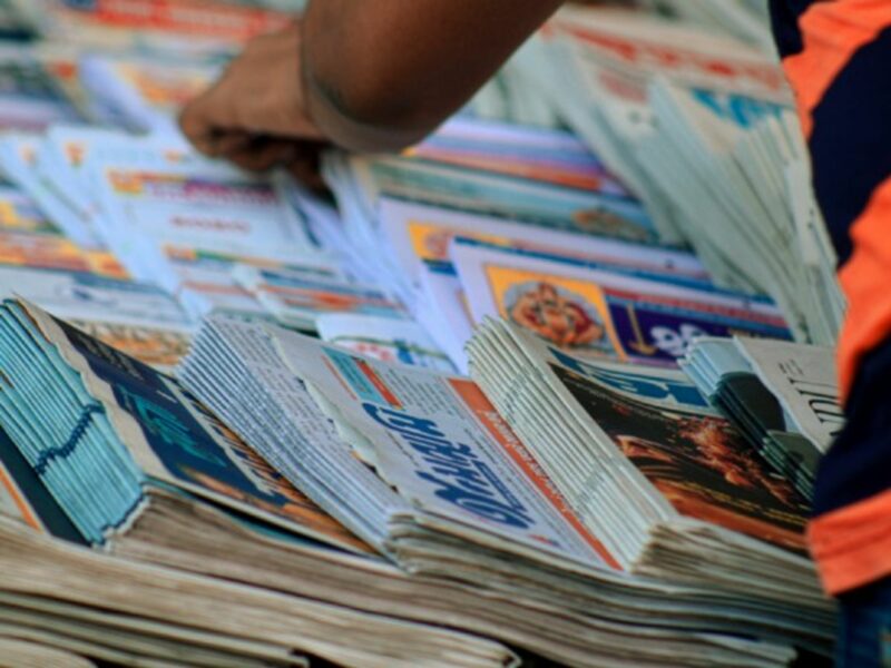 A man searches through stacks of newspapers.