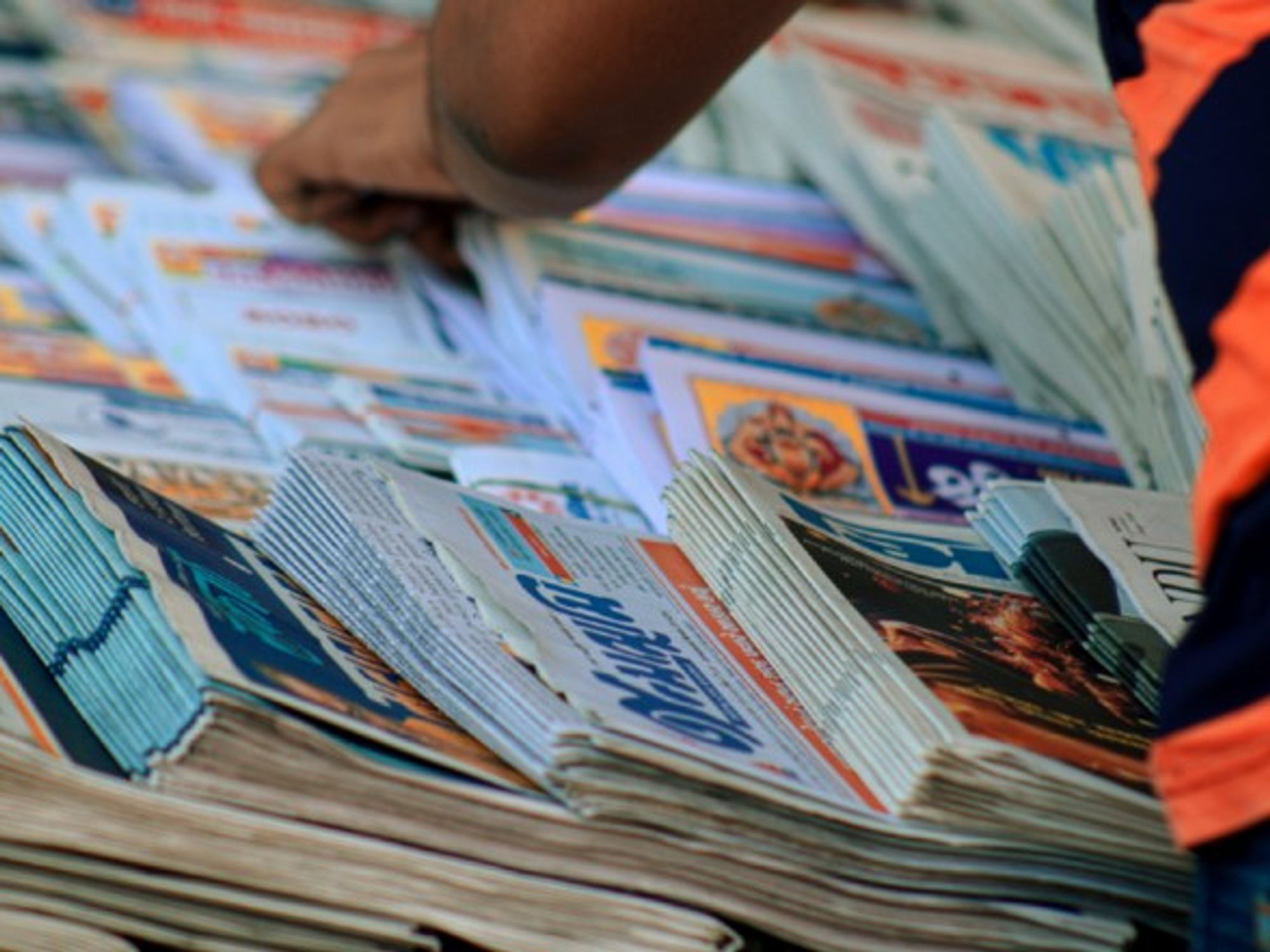 A man searches through stacks of newspapers.