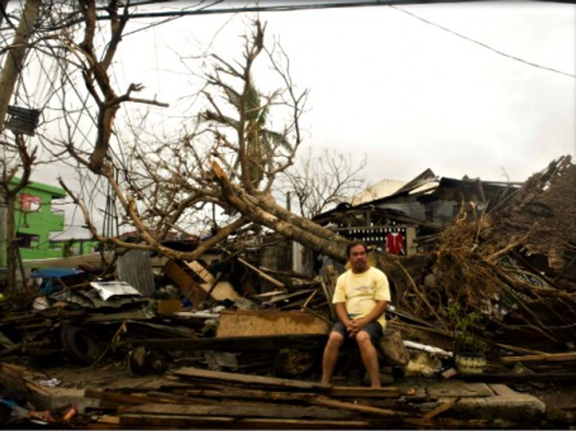 A man sits on debris of his house in Leyte province, central Philippines