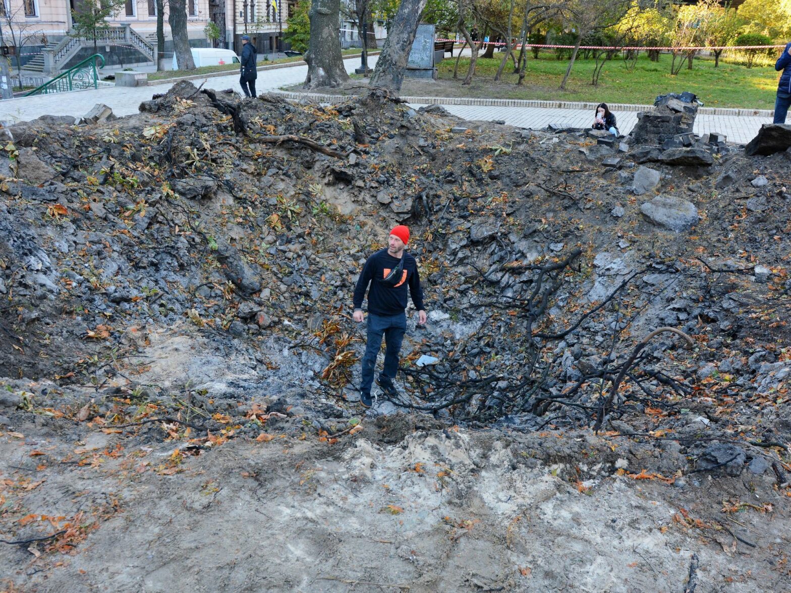 a man stand in the middle of the crater left by a russian rocket on a kids' playground in Kyiv