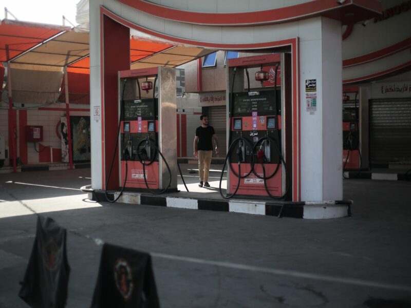A man stands between two gas pumps at an empty and closed gas station
